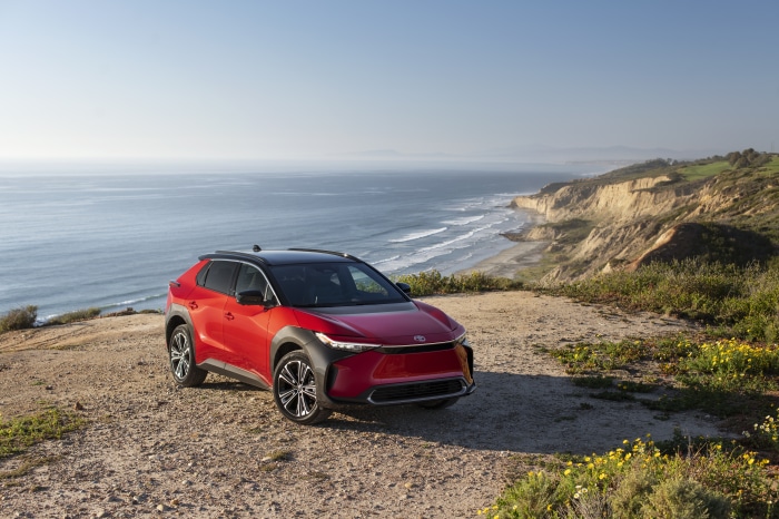 Red Toyota BZ4X parked on a cliff overlooking the ocean