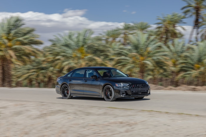 Audi S8 driving on a road with palm trees