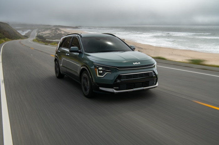 Green Kia Niro driving on coastal road