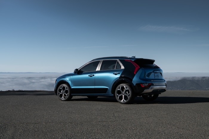 Blue Kia Niro parked on a road with clouds below