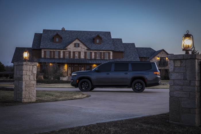 Jeep Wagoneer L parked in front of a stone house at dusk