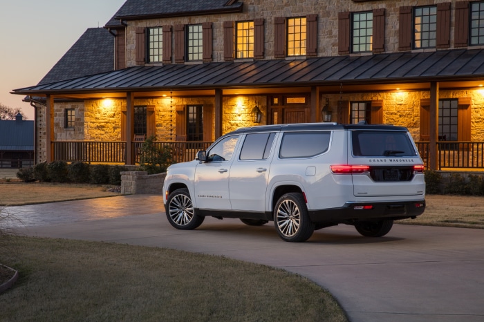 White Grand Wagoneer parked in front of a stone house