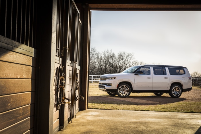 White Jeep Grand Wagoneer parked outside a stable