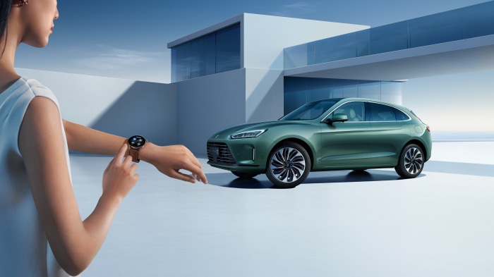 Woman using smartwatch near AITO M5 car