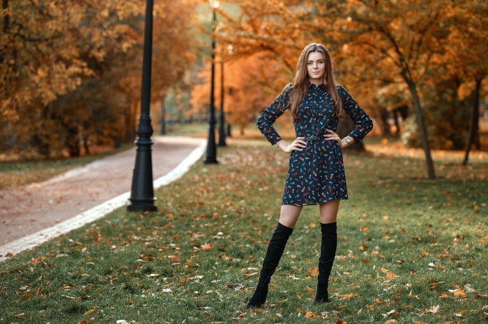 Woman in dress and boots in autumn park