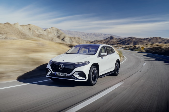 White Mercedes-Benz EQS SUV driving on a desert road