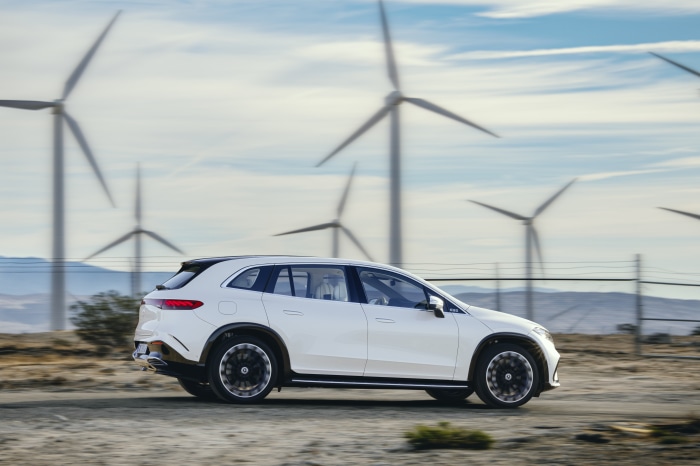 White Mercedes-Benz EQS 450+ 4K driving near wind turbines