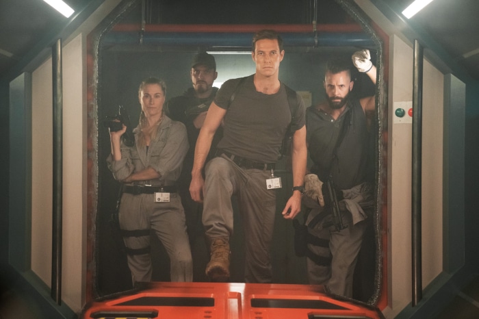 Luke Bracey and crew in a spaceship corridor