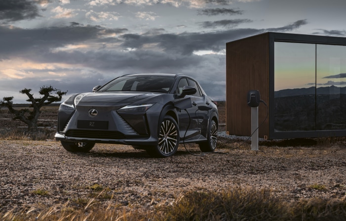 Lexus RZ 450e charging next to a modern cabin