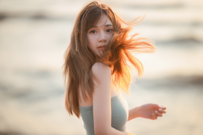 Young Asian woman with windblown hair at sunset