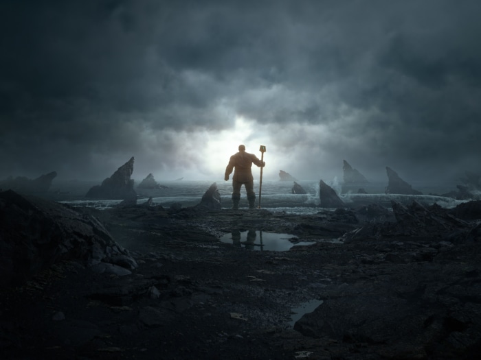 Thanos with a staff on a rocky shore