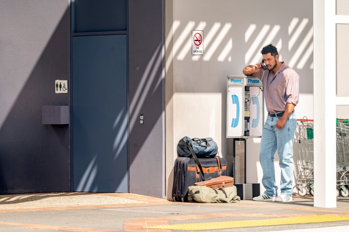 Uli Latukefu on the phone with luggage