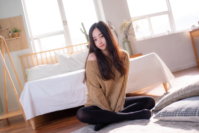 Asian woman in sweater sitting on floor