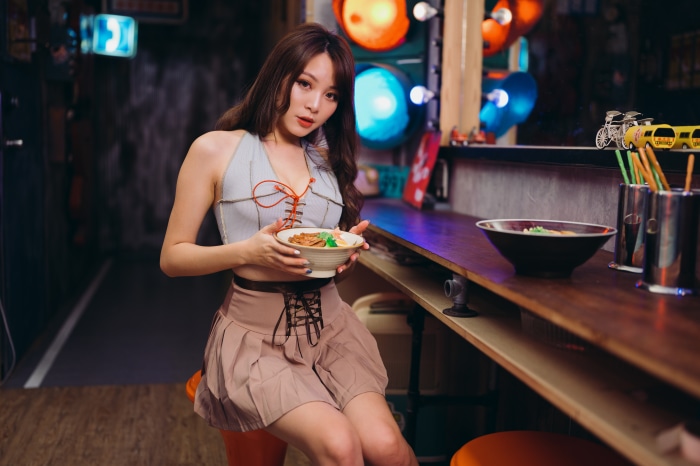 Asian woman holding a bowl of food at a bar