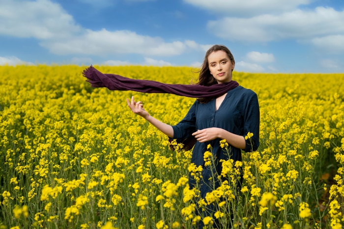 Woman in a field of yellow flowers with a scarf