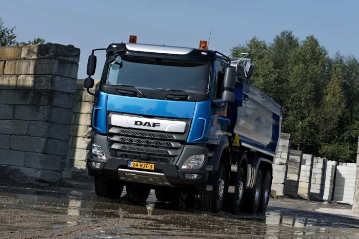 Blue DAF HD dump truck driving through mud