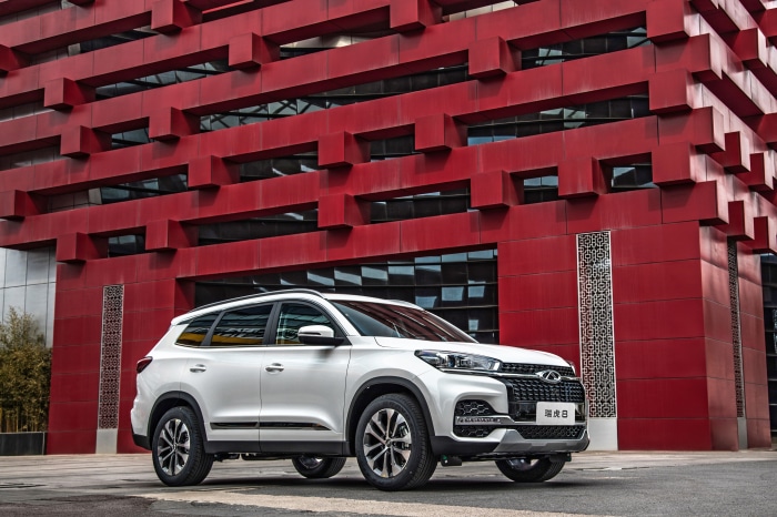 White Chery Tiggo 8 SUV in front of red building
