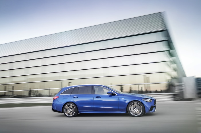 Blue Mercedes-AMG C 43 Estate driving past modern building