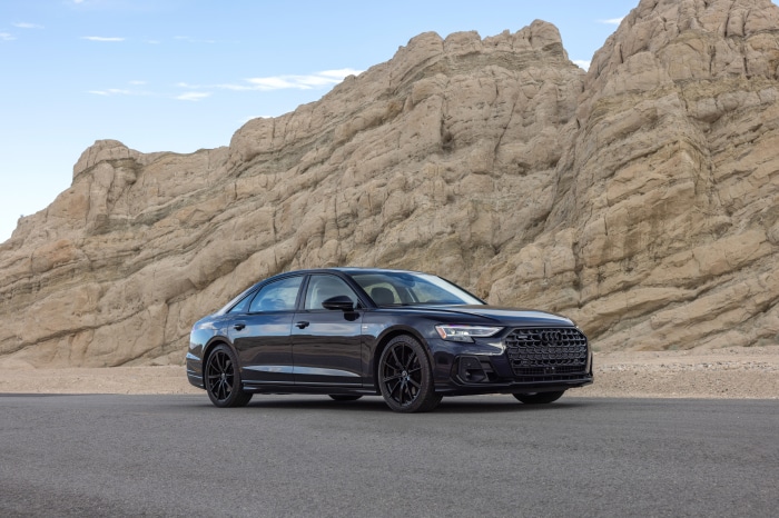 Audi A8 sedan parked on a road with rocky mountains