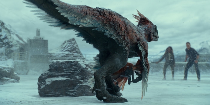Feathered dinosaur attacks people in snowy landscape