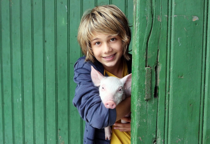 Boy holding a pig in front of a green door