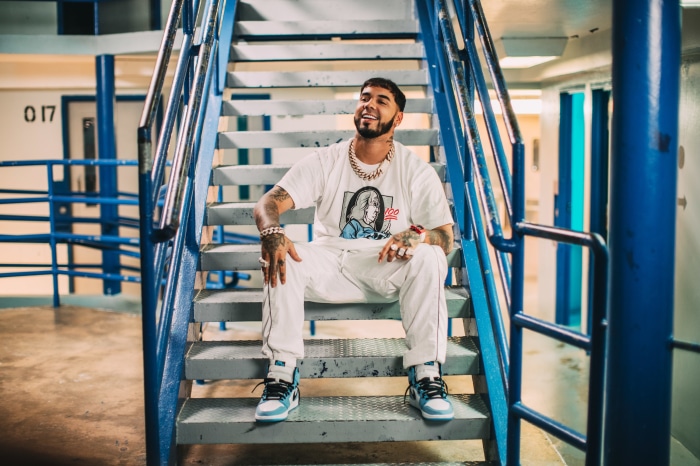 Anuel AA sitting on stairs
