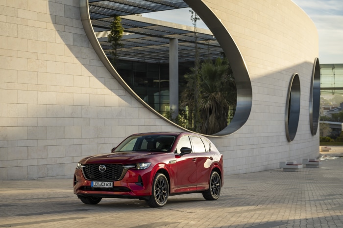 Red Mazda CX-60 parked in front of a modern building
