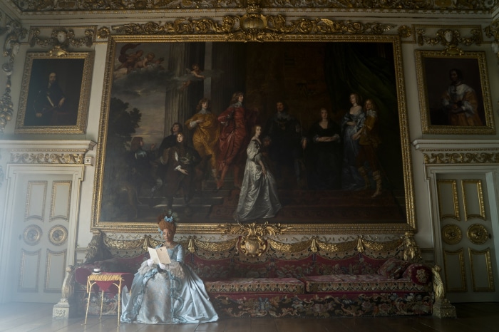 Woman in blue dress reading in opulent room