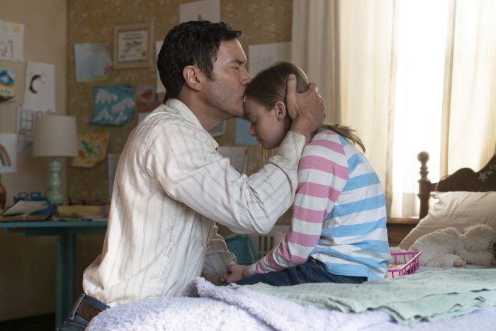 Father kissing daughter in bedroom