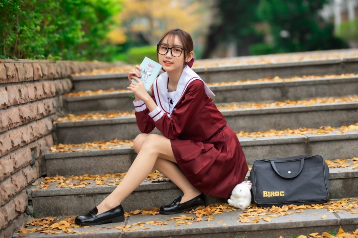 Asian girl in school uniform with book and bag