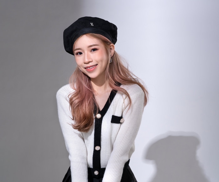 Asian woman wearing a beret and cardigan