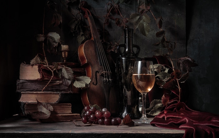 Still life photography with violin, books, and wine