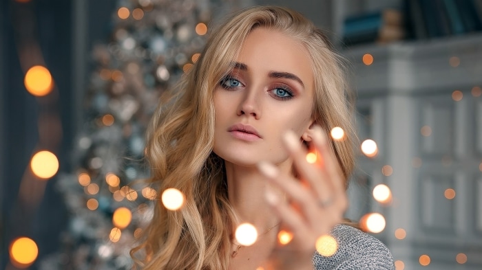 Woman with blonde hair and blue eyes near Christmas lights