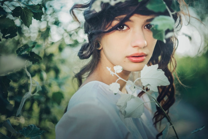 Young woman with dark curly hair and white dress