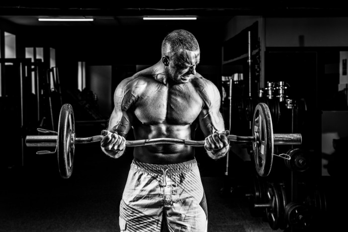 Bodybuilder performing barbell curls in a gym