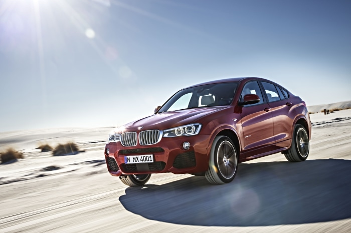 Red BMW X4 xDrive35i driving on a sandy road