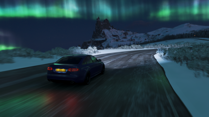 Audi driving on snowy road under aurora borealis