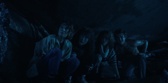 Four people hiding in a dark cave
