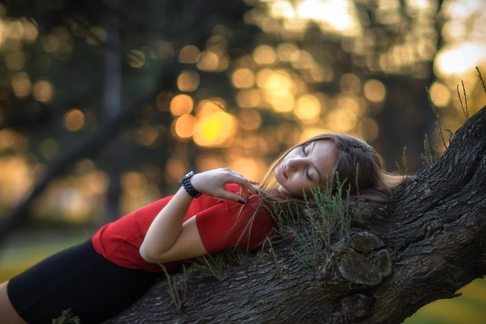 Young woman sleeping on a tree branch