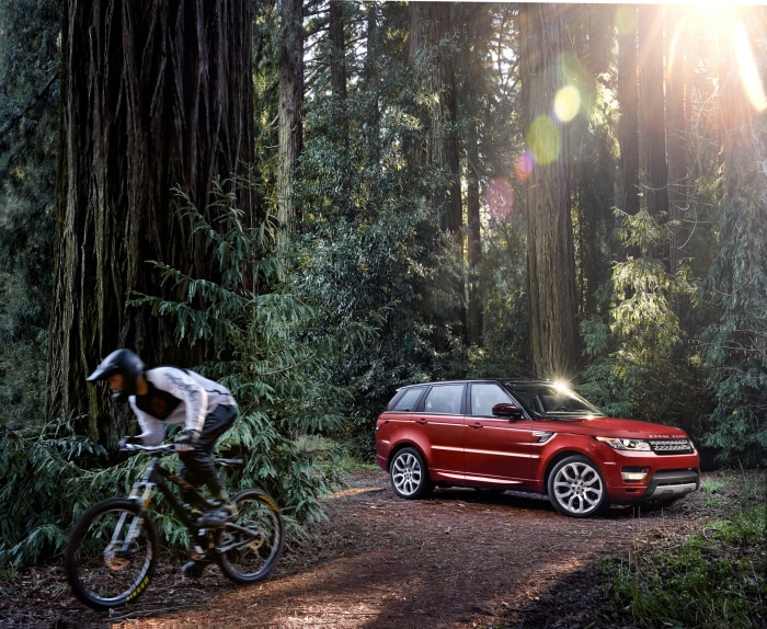 Red Range Rover Sport in Forest with Mountain Biker