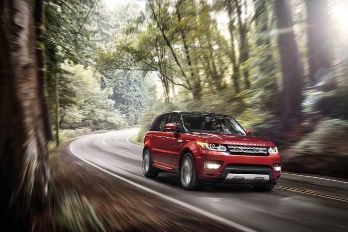 Red Range Rover Sport driving on a forest road