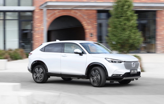 White Honda HR-V driving past brick building