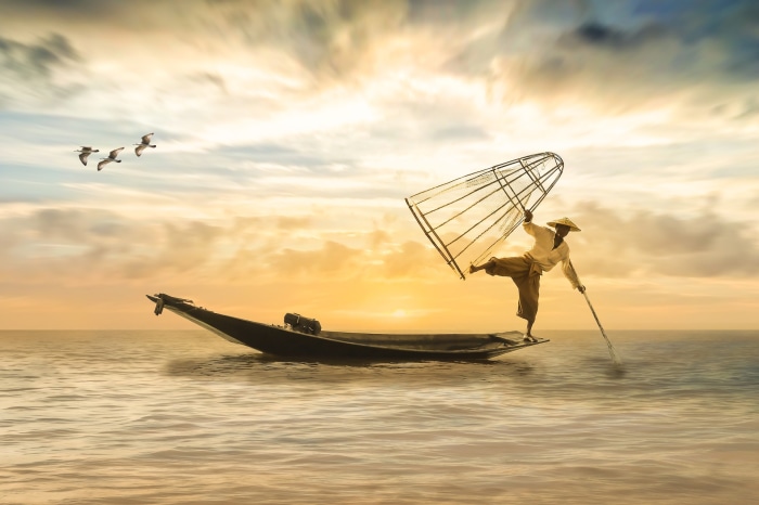 Fisherman on a boat with a net at sunset