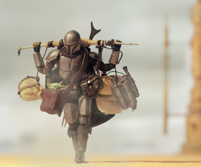 The Mandalorian carrying Grogu and supplies