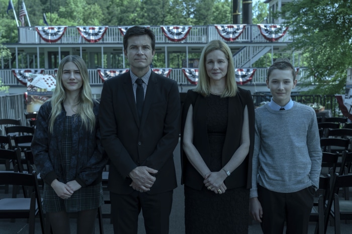 Ozark family standing in front of a boat