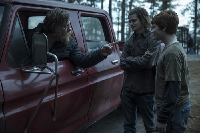 Man in truck pointing at two boys