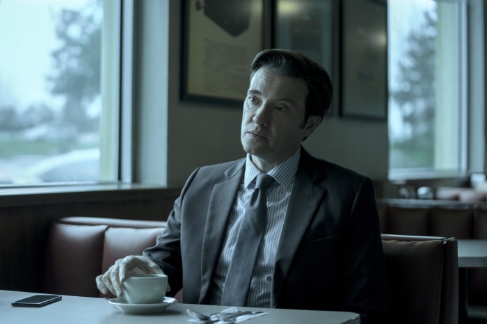 Man in suit sitting at a table with coffee