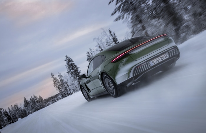 Green Porsche Taycan 4S driving on a snowy road
