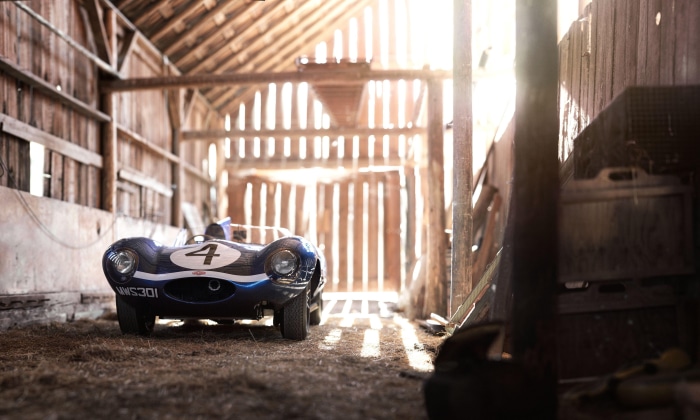 Blue Jaguar D-Type race car with number 4 in a barn