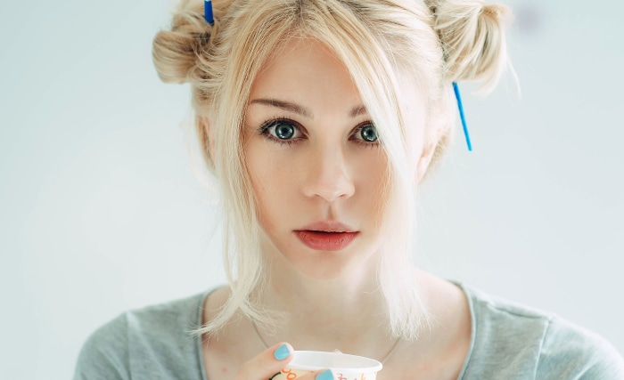 Young woman with blonde hair in buns holding a cup